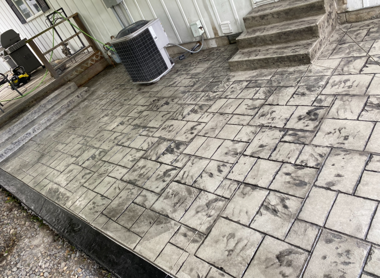 Stamped concrete patio with brick pattern beside home